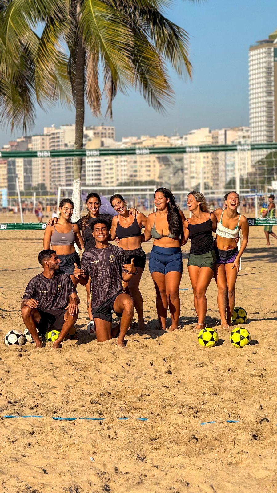 Alunos e treinadores do Shark Rio posando com bolas na areia
